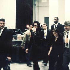 a group of people in suits and ties walking through a room with other people behind them