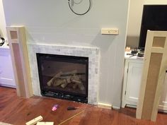 a living room with a fire place next to a wall mounted tv on a wooden floor