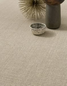 a bowl sitting on top of a rug next to a vase