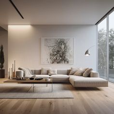 a modern living room with wood floors and large windows on the wall, along with an l - shaped sectional sofa