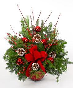 a christmas arrangement with pine cones, berries and evergreens in a red vase on a white background