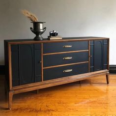 a black and gold sideboard with a vase on top