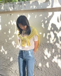 a woman standing in front of a wall with her hands on her hips and looking down