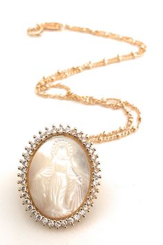 "Virgen la Milagrosa Necklace This eye-catching 1mm 18k gold plated Saturn chain hangs a gorgeous mother of pearl carved oval shape Miraculous Virgin Mary image with luminous clear cubic zirconia stones around it. This necklace is designed to be worn all day. Would be a perfect bride accessory, a gift for your wife, mother, sister, grandmother or as a gift for yourself. DETAILS: Necklace length: 17.5\" inches / 45 cm Pendant diameter: 0.9\"x \"1 inches / 2 x 2.5 cm Other Miraculous Medals are av Miraculous Medal Necklace For Mother's Day Gift, Elegant Miraculous Medal Necklace, Miraculous Medal Jewelry Gift For Mother's Day, Mother's Day Gift Jewelry With Miraculous Medal, Elegant Miraculous Medal Pendant Necklace, Elegant Miraculous Medal Jewelry For Gift, Elegant Pendant Necklace With Miraculous Medal, Elegant Miraculous Medal Jewelry Gift, Spiritual Gold-plated Jewelry For Mother's Day