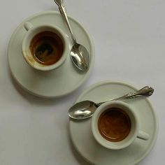 two cups of coffee on saucers with spoons