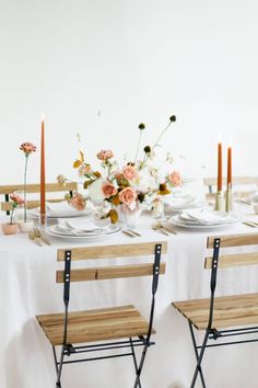 two wooden chairs sitting next to each other on top of a white table covered in flowers