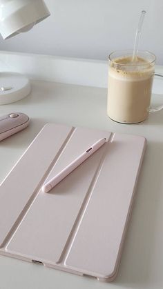 a pink tablet with a pen on it next to a cup of coffee