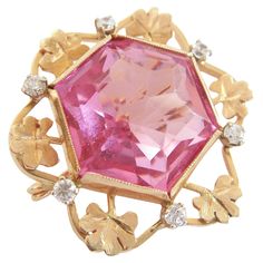 Retro 14K yellow gold custom made brooch - set with one hexagonal cut pink crystal (approx. 24 carats - 20 mm. x 17 mm. x 13 mm. deep) - surrounded by gold chased sprigs of clover and six claw set clear crystals (approx. 1/3 carat total - 2 mm. diameter each) - beautifully finished back with twisted rope detail - original pin with custom spring hinge and 'c' catch - signed 'A.M.' (unidentified maker) - acid tested for gold purity - Italy (likely) - circa 1960's. Excellent vintage condition - couple of chips to the pink crystal (likely an older crystal reset in this brooch) - no loss - no damage - no repairs - signs of age and use - ready to wear. Size/Dimensions - Medium - 1 1/4" (3.2 cm.) Diameter x 5/8" (1.6 cm.) Deep (Including Pin). Weight - 13.65 Grams (Total). Crystal Brooch, 3 Carat, Pink Crystal, Clear Crystal, Aging Signs, 1960s, Yellow Gold, Italy, Crystals