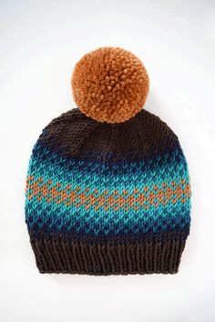 a knitted hat with a pom - pom sitting on top of it