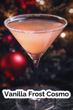 a close up of a drink in a glass near a christmas tree with the words vanilla frost cosmo on it