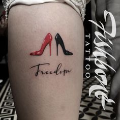 a woman's leg with a tattoo that reads, freedom and two high heeled shoes