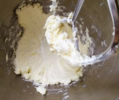 a mixing bowl filled with white batter and a metal spoon in the middle of it