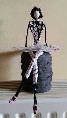 a small doll sitting on top of a black rock next to a radiator