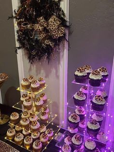 a table topped with lots of cupcakes covered in frosting and leopard print