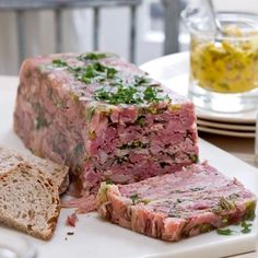 a meatloaf sandwich cut in half on a white plate with bread and water