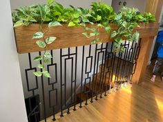 a planter with green plants on the top of a stair case in a house