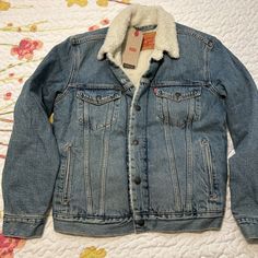 Elevate your denim game with this Levi's Unisex Sherpa Denim Trucker Jacket. The jacket features a classic blue denim color and is made with high-quality cotton and denim fabric. It comes in a size small, making it the perfect fit for regular-sized adults. The jacket also includes a variety of features such as a hood, zippered pockets, and a unisex design, making it a versatile addition to any wardrobe. Whether you're looking for a stylish denim jacket or a cozy sherpa fleece, this Levi's jacket has got you covered. Please be sure and see all measurements Winter Streetwear Washed Blue Denim Jacket, Winter Denim Blue Cotton Denim Jacket, Denim Blue Cotton Jacket With Pockets, Winter Cotton Jeans With Pockets, Winter Blue Jeans With Button Closure, Winter Jeans In Denim Blue With Button Closure, Winter Washed Blue Outerwear For Streetwear, Cotton Denim Blue Jeans For Winter, Winter Cotton Jeans In Denim Blue