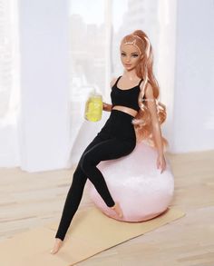 a barbie doll sitting on top of a pink ball with a bottle in her hand