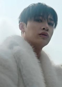 a man with black hair wearing a white fur coat