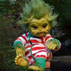 a troll doll with green hair sitting on someone's lap and holding it in the air