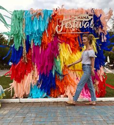 a woman walking past a colorful backdrop with streamers