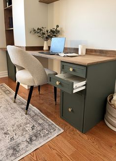 a desk with a laptop on it and a chair in front of it, next to a rug