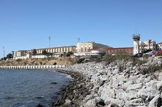 there is a lighthouse on top of the hill next to the water and buildings in the background