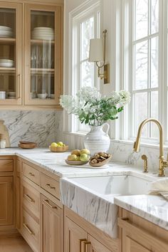 a kitchen with marble counter tops and wooden cabinets, along with white flowers in a vase