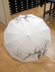 an open umbrella sitting on top of a hard wood floor next to filing cabinets and drawers