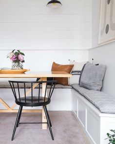 a table and bench in a room with white walls