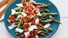 a blue plate topped with asparagus, tomatoes and parmesan cheeses