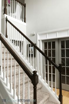 a white staircase with black railing and glass doors