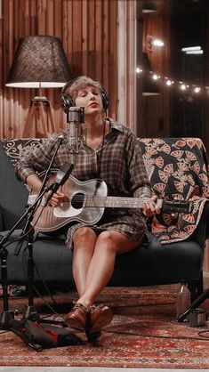 a person sitting on a couch with a guitar in front of a microphone and headphones