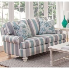 a blue and white striped couch sitting in front of a window with pillows on it