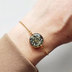 a close up of a person's wrist wearing a gold bracelet with flowers on it