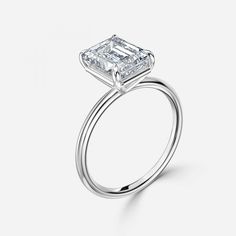 an engagement ring with a princess cut diamond in the center, on a white background