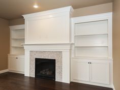 an empty living room with built - in bookshelves and fireplace