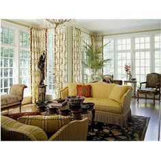 a living room filled with lots of furniture next to large window covered in drapes