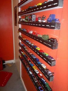 there are many toy cars on the shelves in this room that is painted orange and has red walls