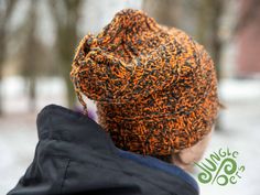 a young child wearing a knitted orange and black beanie looking at the snow