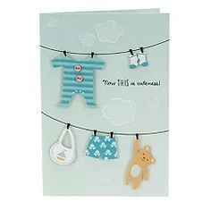 a greeting card with clothes and baby items hanging from a line, on a white background