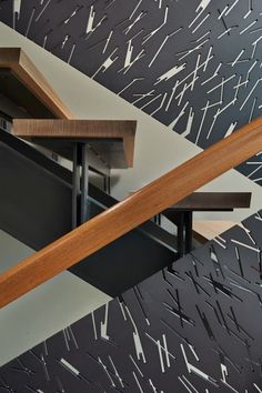 an artisticly designed stair case with wooden handrails and black and white tiles on the wall