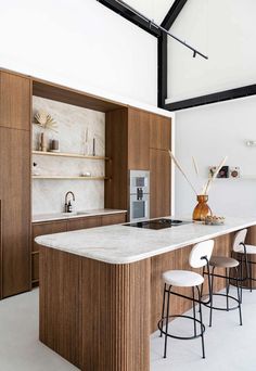 a kitchen with an island counter and stools next to it in the middle of the room