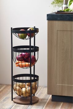 three tiered rack with donuts and apples on it in front of a cabinet