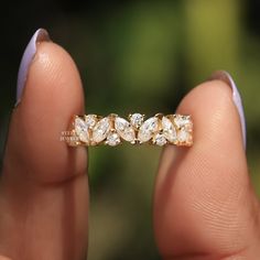 a woman's hand holding a gold ring with three diamonds on it and two fingers