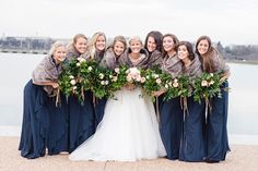 a group of women standing next to each other in front of a body of water