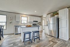 a kitchen with two stools in front of an island and refrigerator freezer next to it