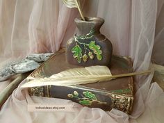 an old book with a feather quill on it next to a vase and some other items