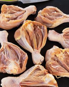 several pieces of raw chicken sitting on top of a black surface next to a knife