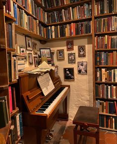 a room filled with lots of books and a piano in front of a book shelf